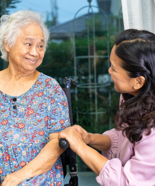Caregiver help Asian senior woman on wheelchair with love at home.